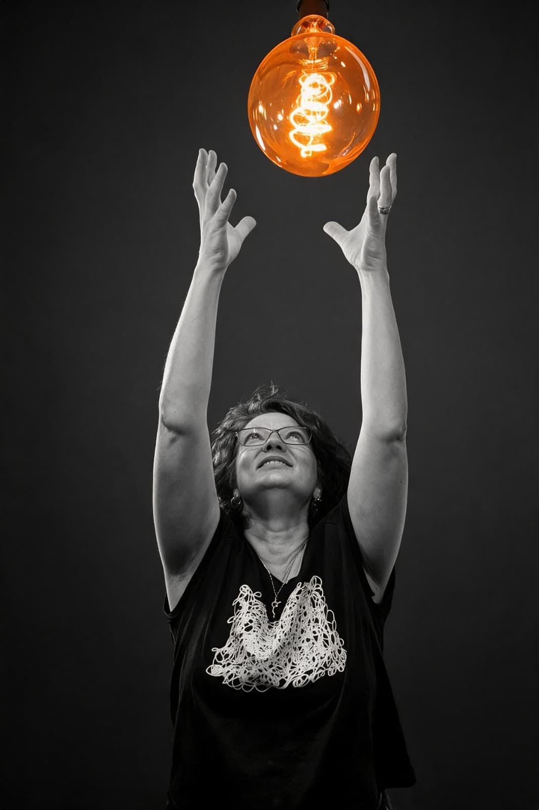 TGV-Media team member reaching toward an illuminated bulb