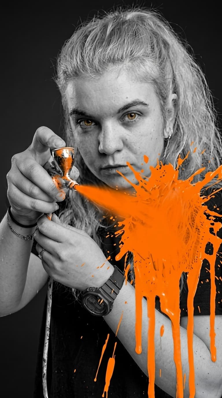 TGV-Media team member using an airbrush with orange paint